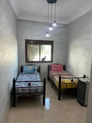 a bedroom with two beds and a window at Steps to the beach in Sidi Rahal