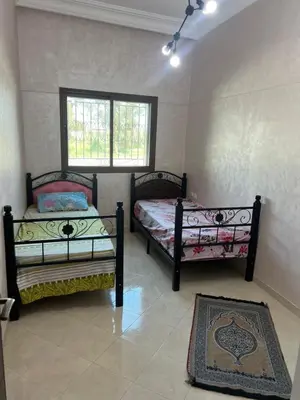 a bedroom with two beds and a window and a rug at Steps to the beach in Sidi Rahal