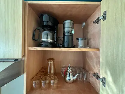 a cabinet with a coffee maker and glasses in it at CosmoStay Airport Casablanca Appart in Nouaseur