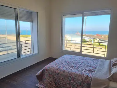 a bedroom with two windows and a bed with a view of the ocean at Apartment Ocean View in O Ben Slimane
