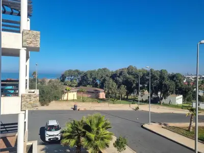 a white car parked in a parking lot near the ocean at Apartment Ocean View in O Ben Slimane