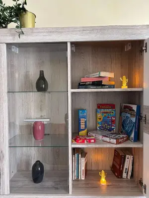 a wooden book shelf with glass shelves and books at Apartment with pool view, 1 min to beach, private parking in Pont Blondin