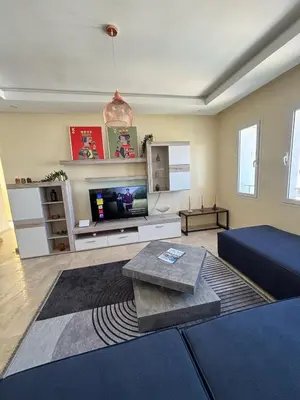 a living room with a couch and a tv at Apartment with pool view, 1 min to beach, private parking in Mansouria