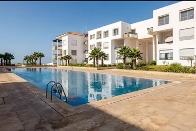 an empty swimming pool in front of a building at Apartment with pool view, 1 min to beach, private parking in Mansouria
