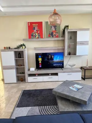 a living room with a flat screen tv on a entertainment center at Apartment with pool view, 1 min to beach, private parking in Mansouria