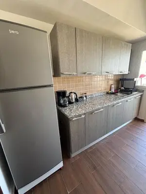 a kitchen with a stainless steel refrigerator and wooden floors at Apartment with pool view, 1 min to beach, private parking in Mansouria