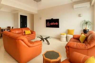 a living room with two orange chairs and a tv at Casablanca in panoramic mode in Casablanca
