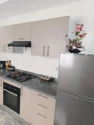 a kitchen with white cabinets and a stainless steel refrigerator at Appartement Golden Beach-Dahomey in Bouznika