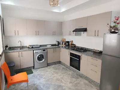 a kitchen with white cabinets and a washer and dryer at Appartement Golden Beach-Dahomey in Bouznika