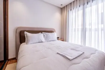 a white bed with two towels on top of it at Design 1BR Living Home M5 Stadium Balcony & Private Parking in Maarif
