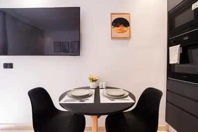 a black table with black chairs in a kitchen at Design 1BR Living Home M5 Stadium Balcony & Private Parking in Maarif