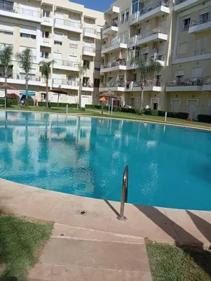 a swimming pool in front of a large apartment building at Appartement vue panoramique in Bouznika