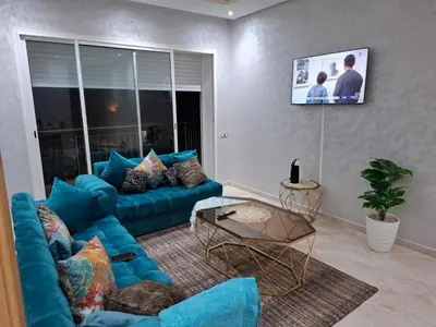 a living room with a blue couch and a tv at Appartement vue panoramique in Bouznika