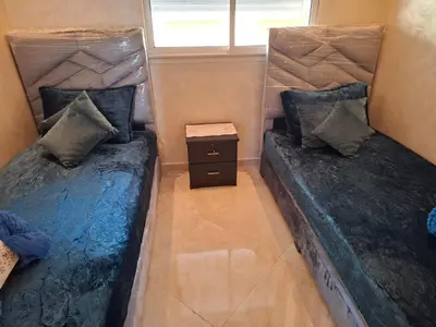 two twin beds in a small room with a window at Appartement vue panoramique in Bouznika