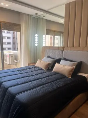 a bedroom with a large bed with blue sheets and pillows at Furnished studio with pool in Nouaseur