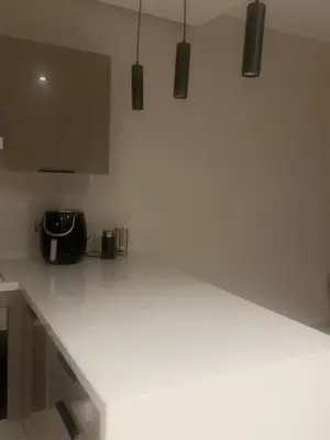a kitchen with a white counter top with lights at Furnished studio with pool in Nouaseur