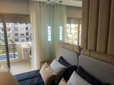 a living room with a couch and a large window at Furnished studio with pool in Nouaseur
