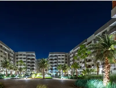 a large building with palm trees in front of it at Furnished studio with pool in Nouaseur