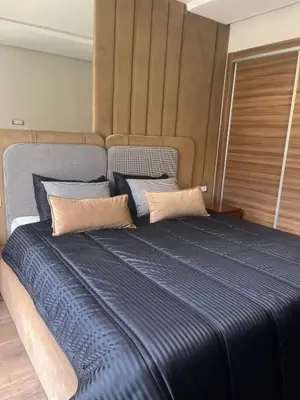 a large bed with blue sheets in a room at Furnished studio with pool in Nouaseur