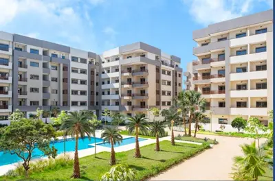 an apartment complex with a swimming pool and palm trees at Furnished studio with pool in Nouaseur