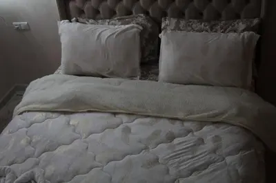 an unmade bed with white sheets and pillows at Aeroport Tissir Appartement in Nouaceur