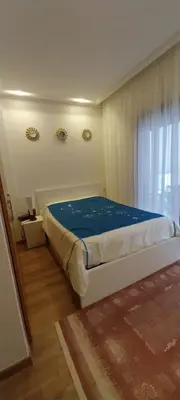 a bedroom with a bed with blue sheets and a window at Residence paradise beach el Mansoria in Mohammedia