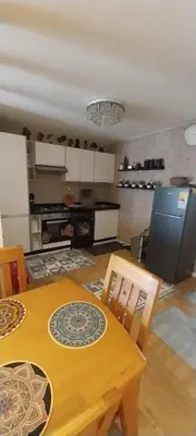 a kitchen with a wooden table and chairs and a kitchen with a stove at Residence paradise beach el Mansoria in Mohammedia
