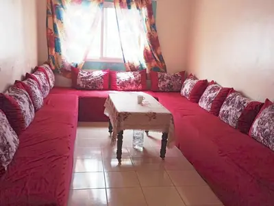 a living room with a red couch with a table at espace chaleureux in Aïn ej Jmel