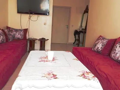 a living room with two red couches and a tv at espace chaleureux in Aïn ej Jmel