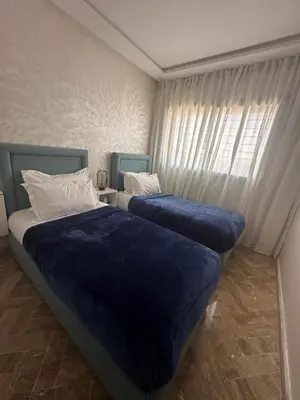two beds in a room with blue sheets and a window at Cosy Stay 15min from Casablanca Airport, in Berrechid in Berrechid