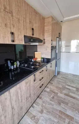 a kitchen with wooden cabinets and black counter tops at Cosy Stay 15min from Casablanca Airport, in Berrechid in Berrechid