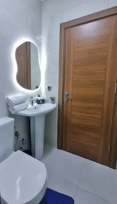 a bathroom with a toilet and a sink and a wooden door at Cosy Stay 15min from Casablanca Airport, in Berrechid in Berrechid