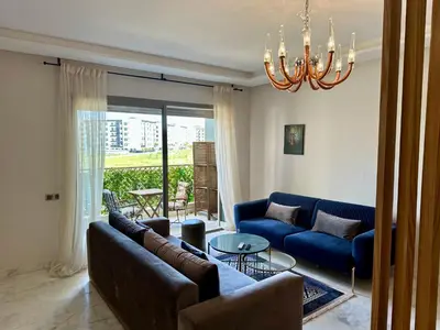 a living room with a blue couch and a chandelier at AeroRelax, free Parking, WI-FI in Nouaseur
