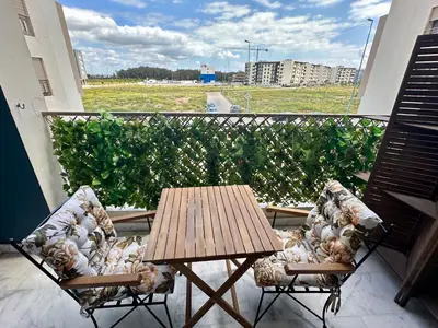 a balcony with a wooden table and two chairs at AeroRelax, free Parking, WI-FI in Nouaseur