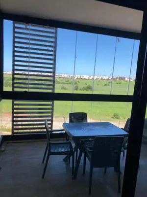 a table and chairs in a room with a large window at Appartement Sidi Rahal Oceanic in Sidi Rahal