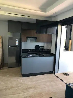 a kitchen with black and white cabinets and a refrigerator at Appartement Sidi Rahal Oceanic in Sidi Rahal