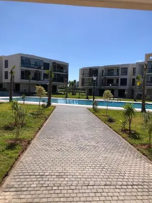 a brick walkway in front of a building with a pool at Appartement Sidi Rahal Oceanic in Sidi Rahal