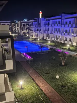 a swimming pool in front of a building at night at Family in Dar Bouazza