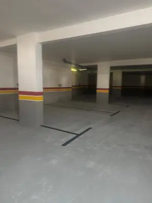an empty parking garage with white floors and columns at Family in Dar Bouazza