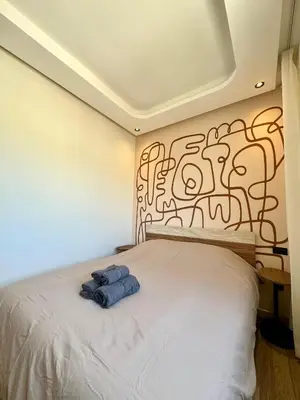 a bedroom with a bed with a painting on the wall at Maarif Picasso Studio & Private Terrace & Parking in Casablanca