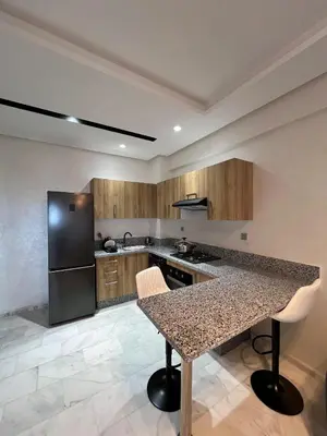 a kitchen with a granite counter top and a black refrigerator at Ocean park zenata in Aïn Harrouda