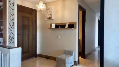a hallway with a door and a chair and a chandelier at Bel appartement in Mohammedia