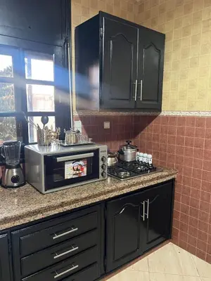 a kitchen with black cabinets and a microwave oven at Longement moderne à Rabat in Rabat