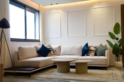 a living room with a white couch and blue pillows at Ain Diab Ocean Breeze & Parking in Casablanca