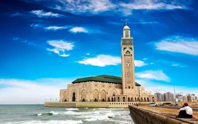 a large building with a clock tower next to the ocean at Ain Diab Ocean Breeze & Parking in Casablanca