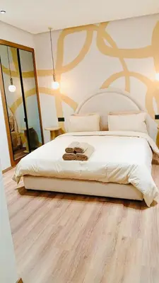 a bedroom with a large white bed and a mirror at Ain Diab Sunrise Nest & Parking in Casablanca