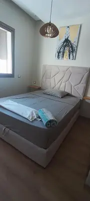 a bedroom with a large bed with a blue blanket on it at Parc mohammedia in Mohammedia