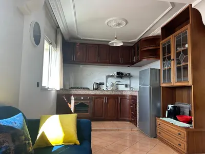 a kitchen with wooden cabinets and a blue couch at Wifaq temara in Temara