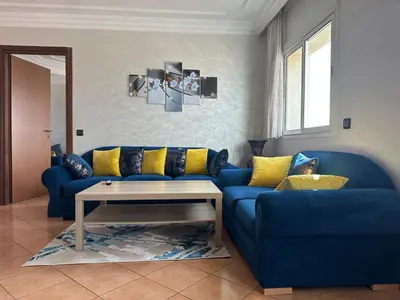 a living room with a blue couch and a table at Wifaq temara in Temara