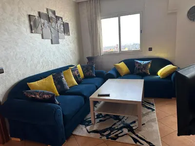 a living room with a blue couch and a table at Wifaq temara in Temara